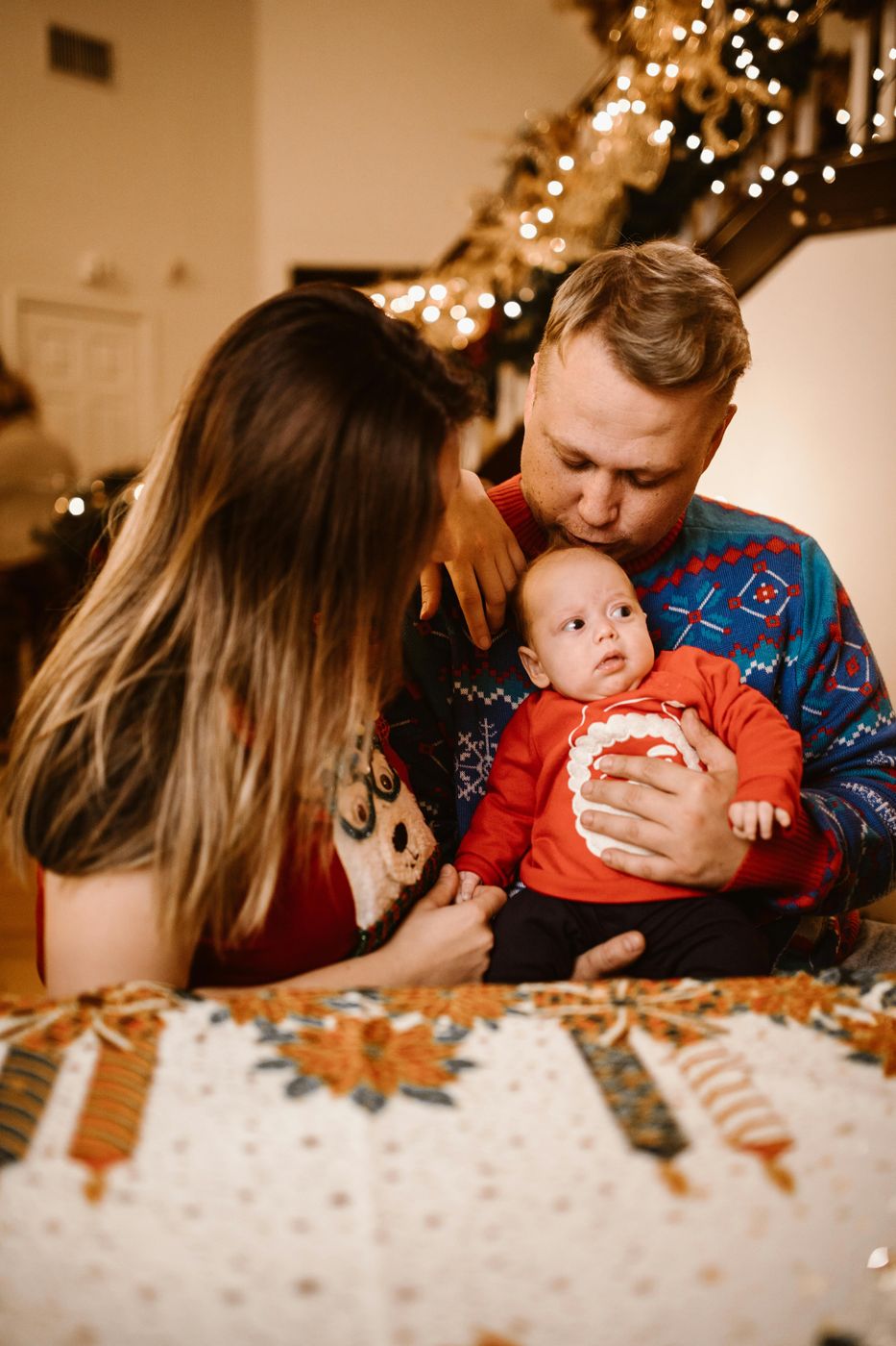 Mama und Papa küssen ihr Baby vor der Lichterkette