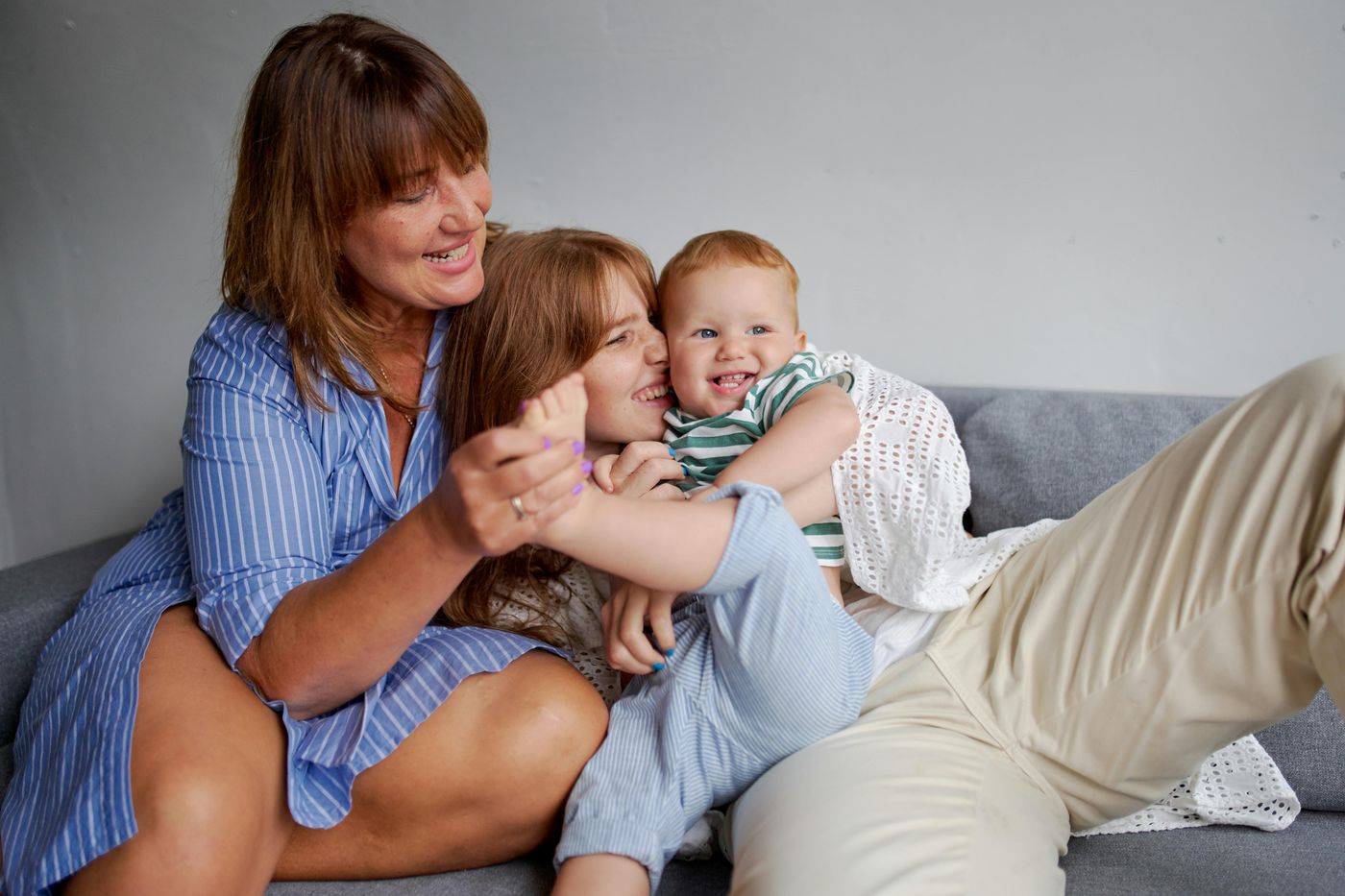 Oma lacht mit ihren Enkeln auf dem Sofa