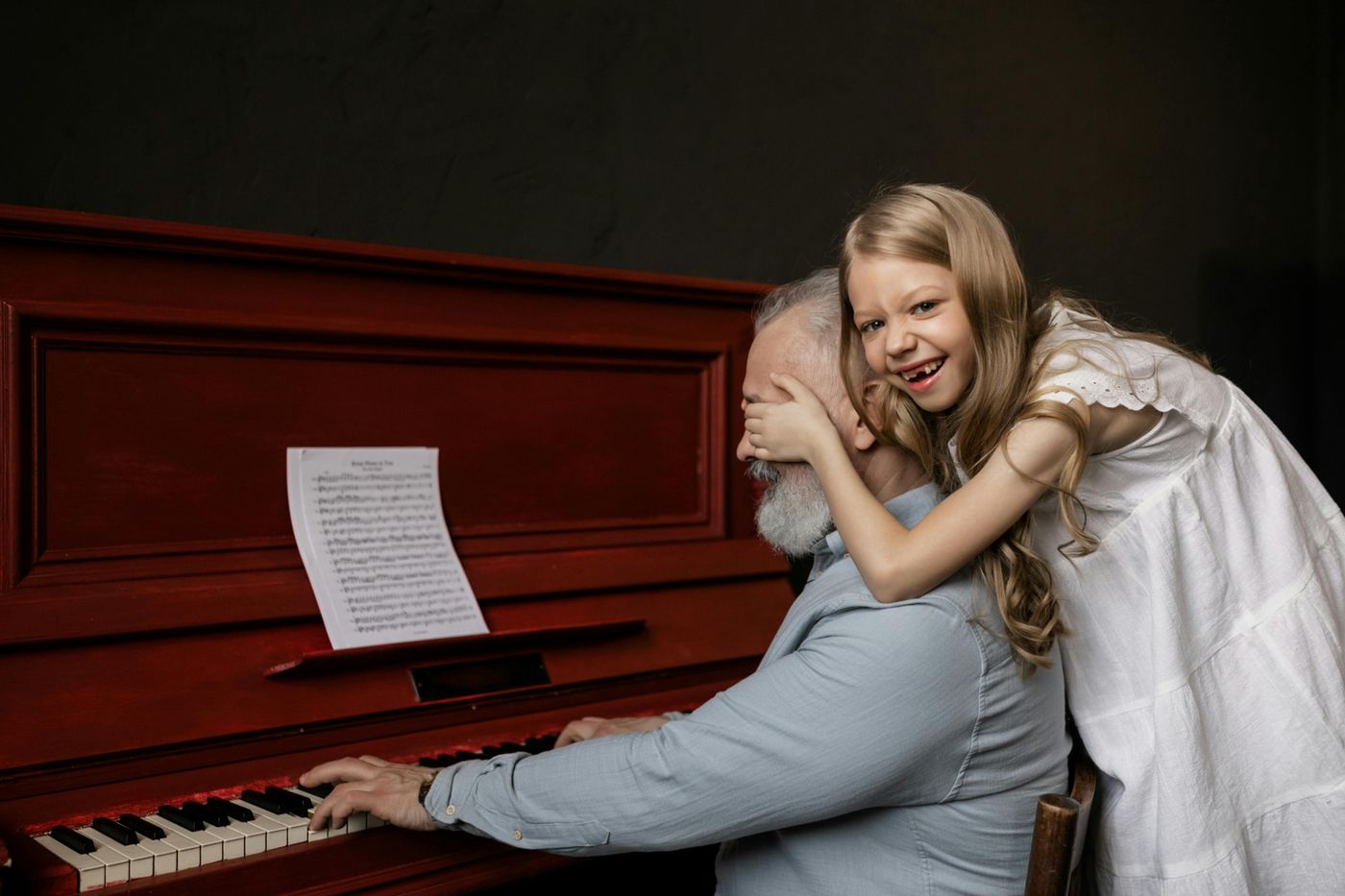 Opa spielt Klavier, die Enkelin umarmt ihn lachend